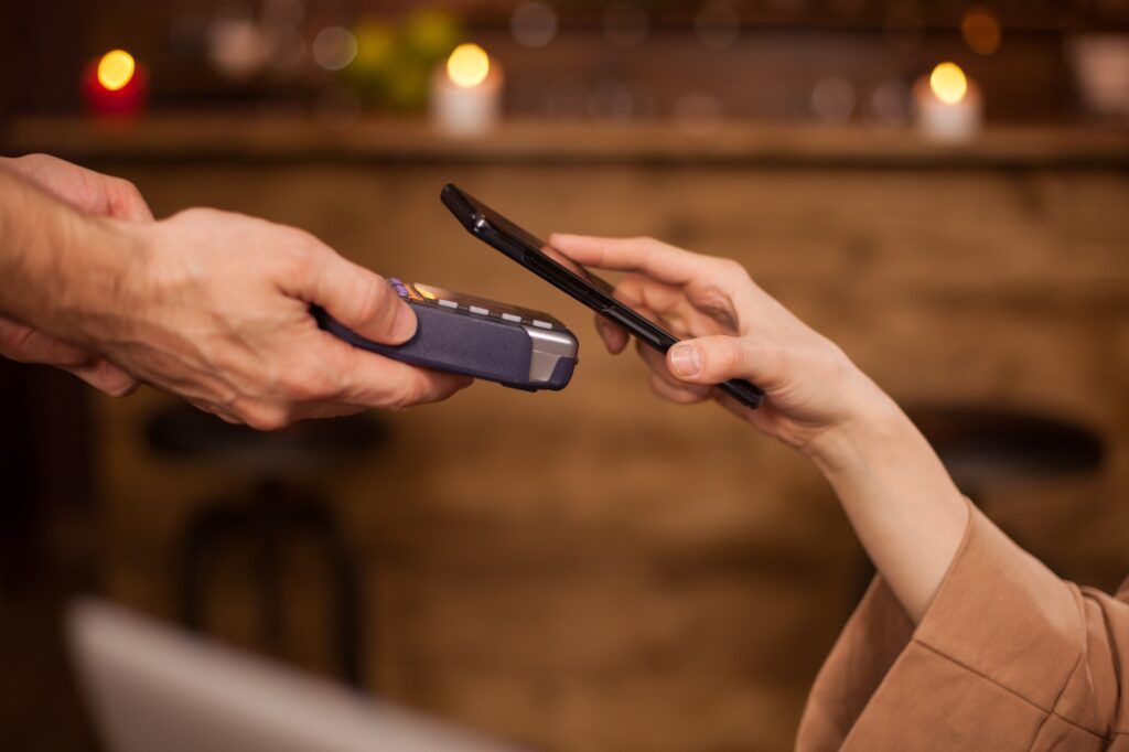 Cropped image of woman paying with mobile phone payment technolgy in a coffee shop